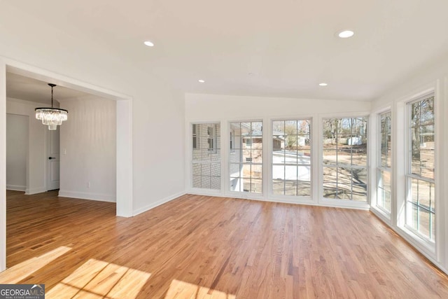 empty room featuring vaulted ceiling, light hardwood / wood-style floors, and a chandelier