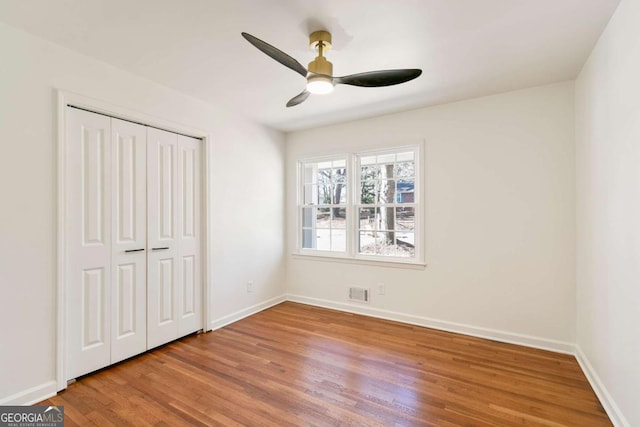 unfurnished bedroom with wood-type flooring, ceiling fan, and a closet