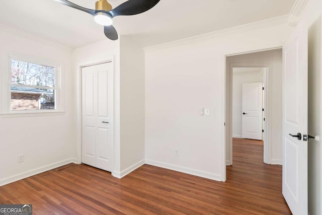 unfurnished bedroom featuring ceiling fan, ornamental molding, dark hardwood / wood-style flooring, and a closet