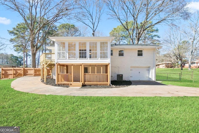 back of property with a garage, a sunroom, and a lawn