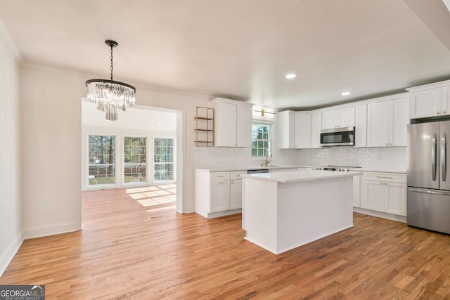 kitchen with white cabinets, hanging light fixtures, a center island, light hardwood / wood-style floors, and stainless steel appliances