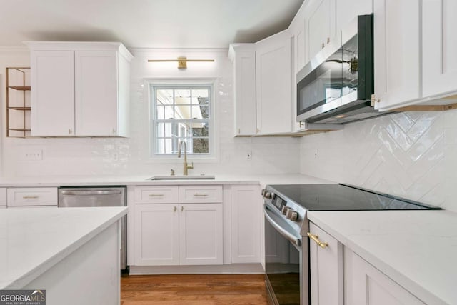 kitchen featuring white cabinetry, sink, light stone counters, and stainless steel appliances