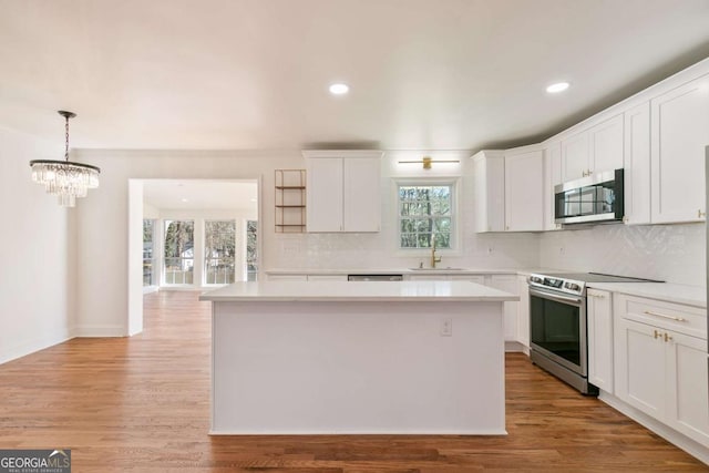 kitchen featuring pendant lighting, sink, appliances with stainless steel finishes, white cabinets, and a kitchen island