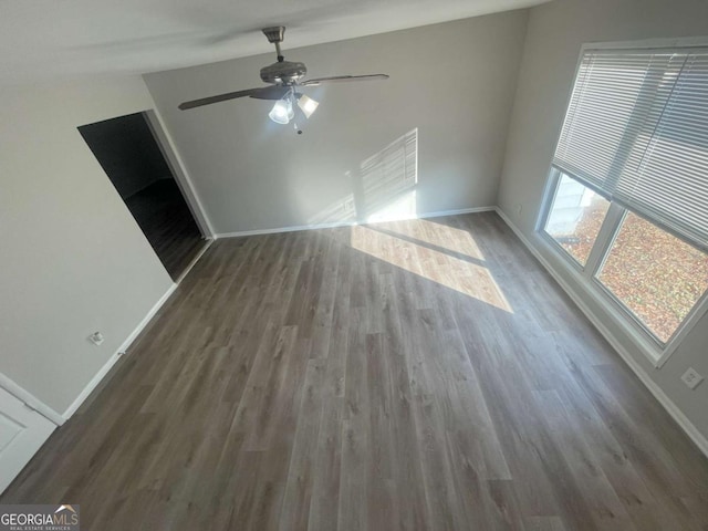 unfurnished living room featuring dark wood-type flooring and ceiling fan