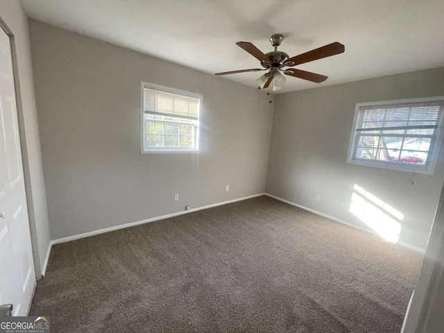 carpeted spare room featuring a healthy amount of sunlight and ceiling fan