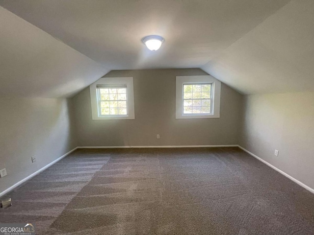 bonus room featuring dark colored carpet, plenty of natural light, and lofted ceiling