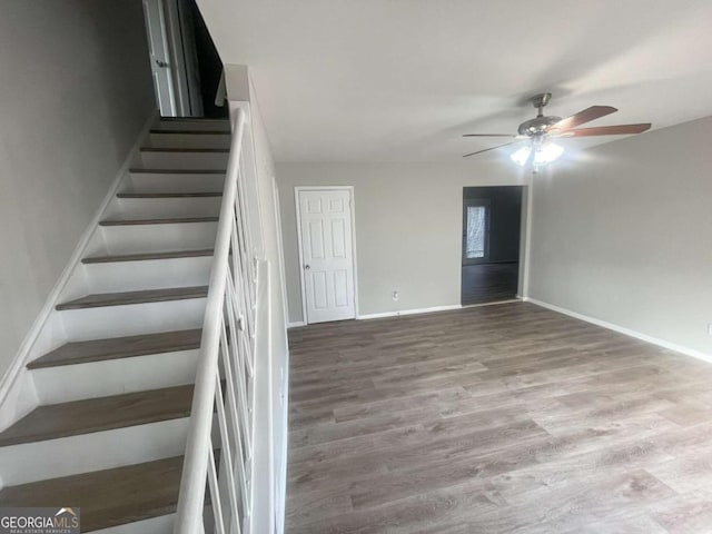 staircase with hardwood / wood-style flooring and ceiling fan