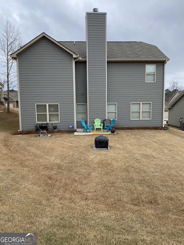 back of property featuring a yard and a fire pit