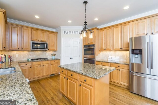 kitchen with light stone counters, a center island, hanging light fixtures, appliances with stainless steel finishes, and light hardwood / wood-style floors