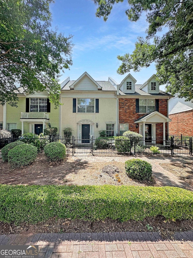 multi unit property featuring a fenced front yard and brick siding