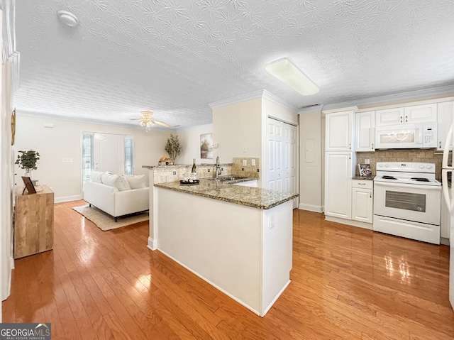 kitchen featuring a peninsula, white appliances, white cabinetry, open floor plan, and light wood-type flooring