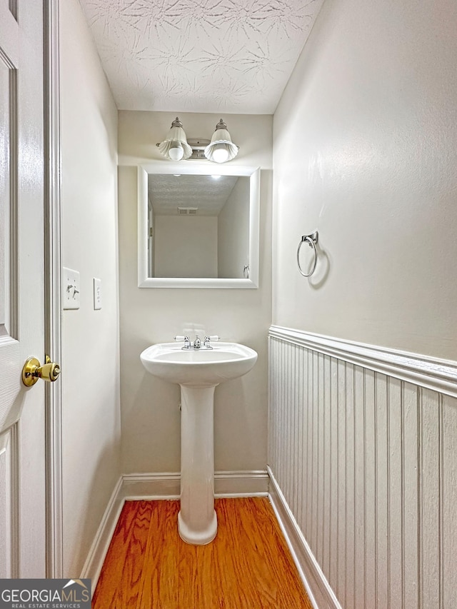 bathroom with visible vents, a sink, a textured ceiling, wood finished floors, and baseboards