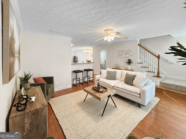 living area with baseboards, stairway, wood finished floors, a textured ceiling, and ceiling fan with notable chandelier