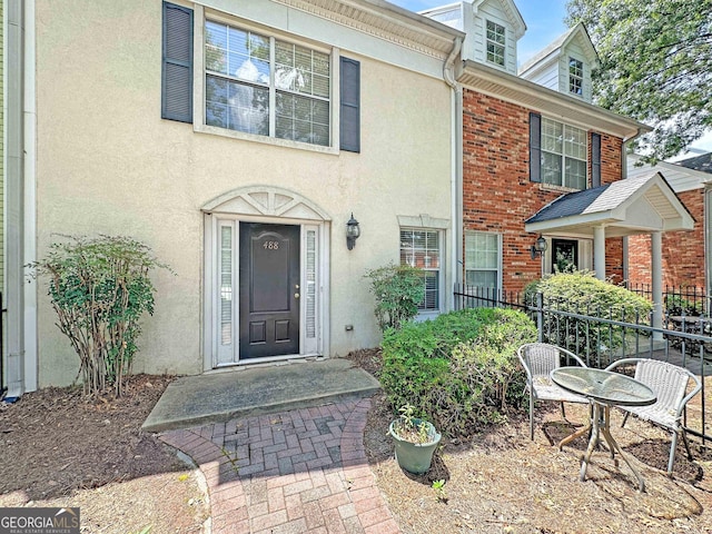 view of front facade with brick siding, fence, and stucco siding