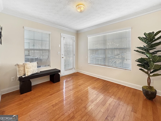 sitting room featuring crown molding, a textured ceiling, baseboards, and wood finished floors