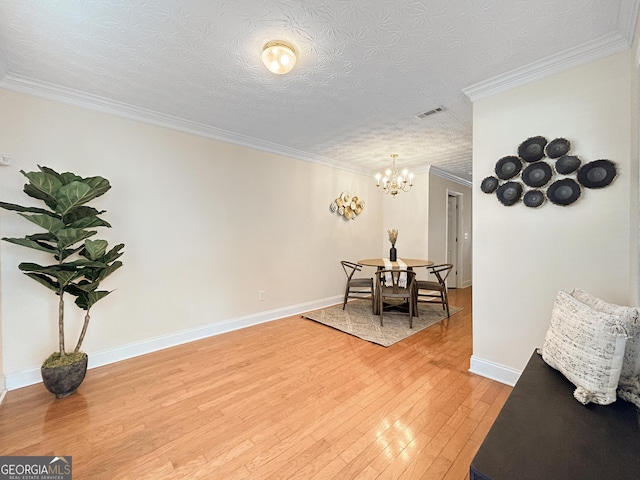 living area featuring visible vents, baseboards, wood finished floors, an inviting chandelier, and crown molding