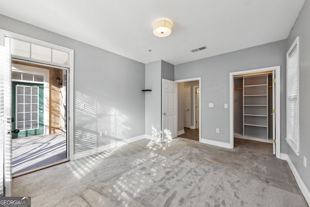 unfurnished bedroom featuring a walk in closet, light carpet, and a closet