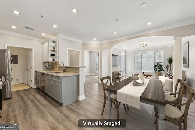 kitchen featuring sink, gray cabinets, appliances with stainless steel finishes, wood-type flooring, and ornate columns