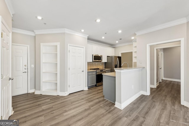 kitchen featuring white cabinetry, crown molding, light wood-type flooring, appliances with stainless steel finishes, and backsplash