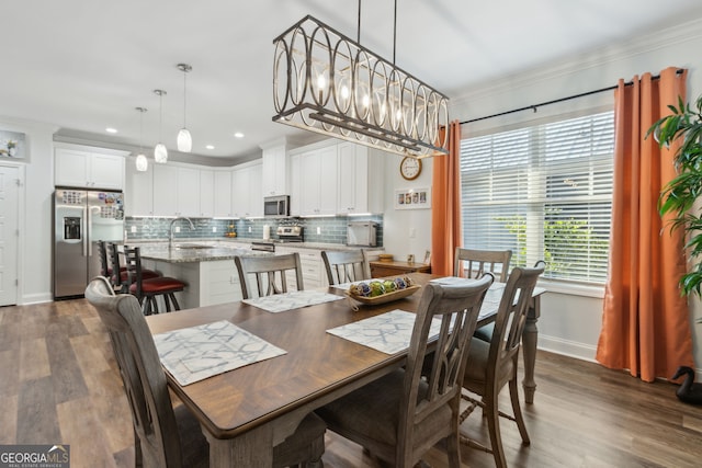 dining space featuring an inviting chandelier, ornamental molding, dark hardwood / wood-style flooring, and sink