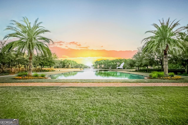 view of property's community with a water view and a lawn