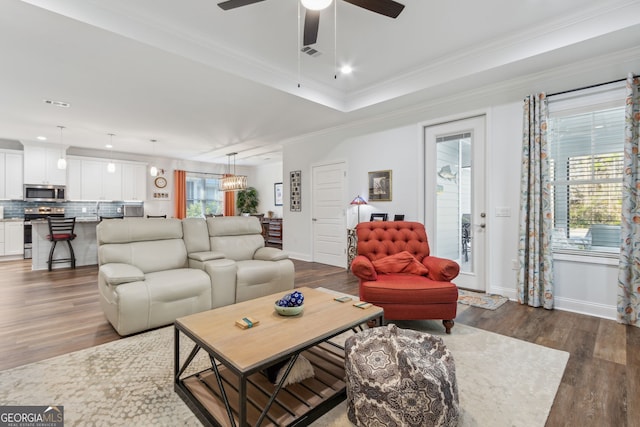 living room featuring a raised ceiling, crown molding, ceiling fan, and dark hardwood / wood-style flooring