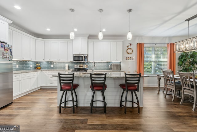 kitchen with white cabinetry, appliances with stainless steel finishes, light stone countertops, and pendant lighting