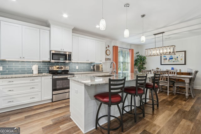 kitchen with white cabinetry, an island with sink, sink, a kitchen bar, and stainless steel appliances