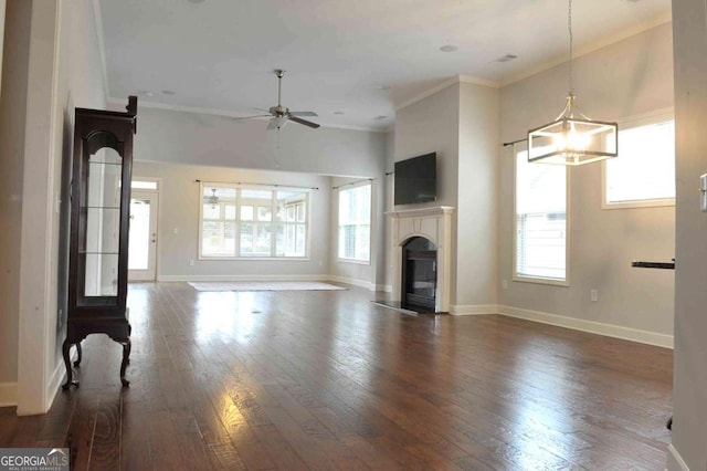 unfurnished living room with ornamental molding, dark hardwood / wood-style flooring, and ceiling fan with notable chandelier