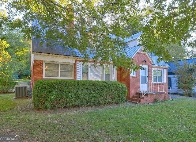 view of front of house featuring central AC unit and a front yard