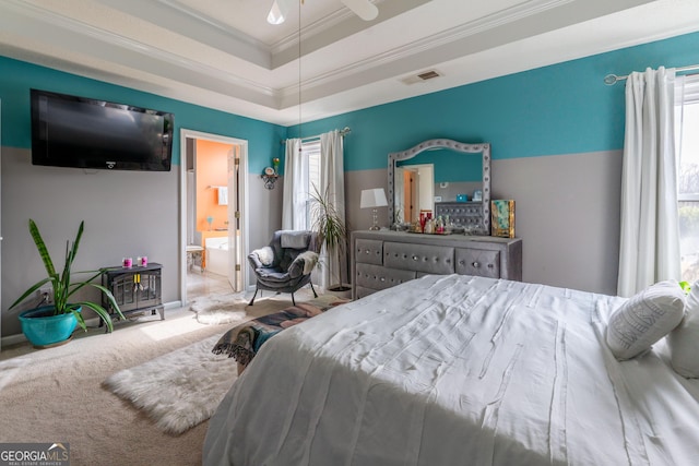 carpeted bedroom featuring ornamental molding, ensuite bathroom, and a tray ceiling