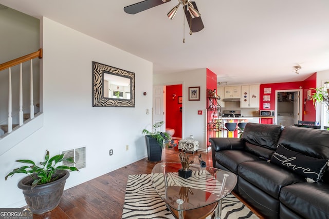 living room featuring dark wood-type flooring and ceiling fan