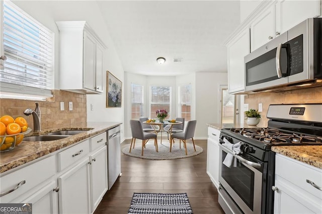 kitchen with light stone counters, appliances with stainless steel finishes, sink, and white cabinets