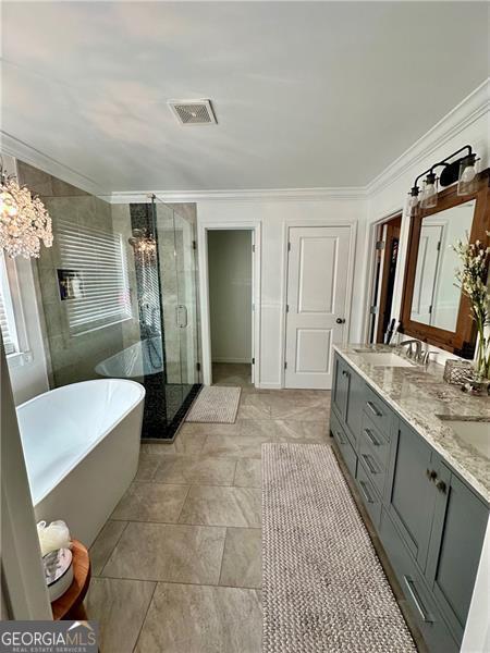 bathroom with vanity, ornamental molding, independent shower and bath, and an inviting chandelier