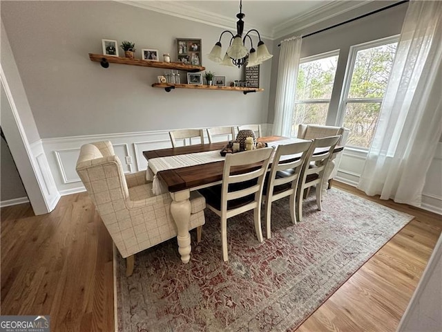 dining room with hardwood / wood-style flooring, crown molding, and an inviting chandelier