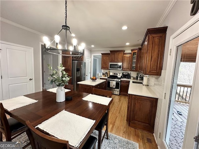 dining area with a notable chandelier, sink, crown molding, and light hardwood / wood-style floors