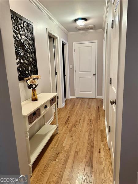 hallway with crown molding and light hardwood / wood-style floors