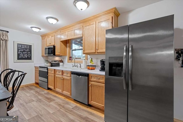 kitchen with appliances with stainless steel finishes, light brown cabinetry, light hardwood / wood-style floors, and sink