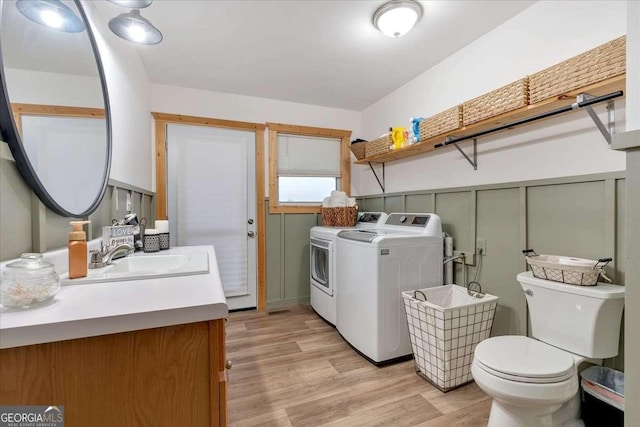 laundry area with sink, washing machine and dryer, and light hardwood / wood-style floors