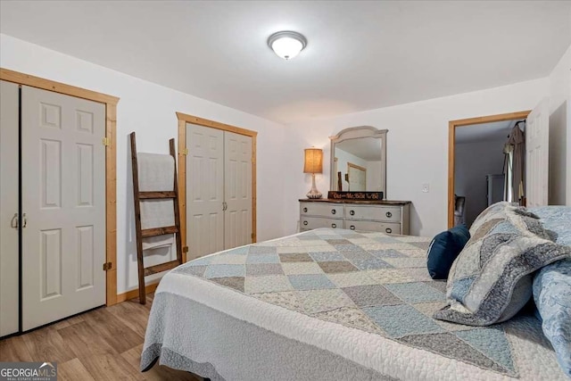 bedroom featuring light hardwood / wood-style floors and multiple closets