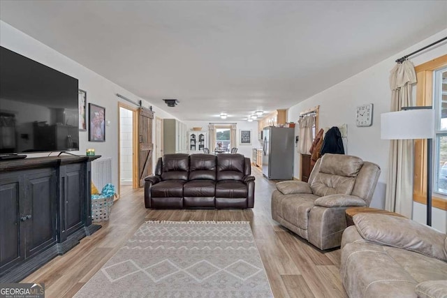 living room with a barn door and light wood-type flooring