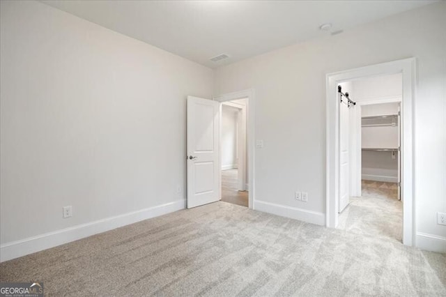 unfurnished bedroom with light carpet, a walk in closet, and a closet