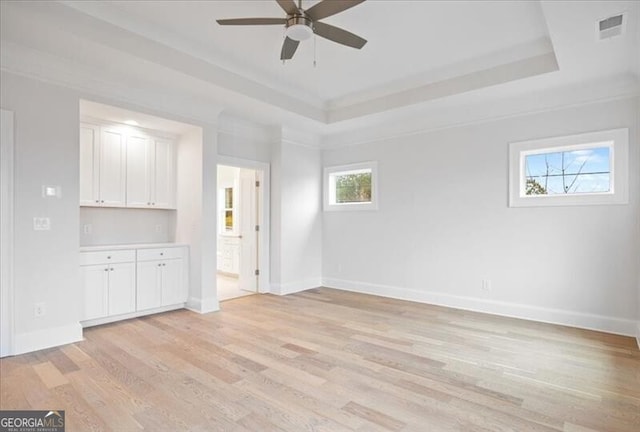 unfurnished room with ceiling fan, a tray ceiling, and light hardwood / wood-style floors