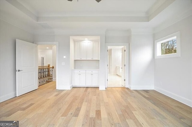 unfurnished living room with crown molding, light hardwood / wood-style flooring, and a raised ceiling