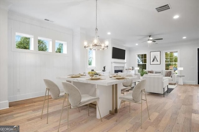 dining room with crown molding, a healthy amount of sunlight, and light wood-type flooring