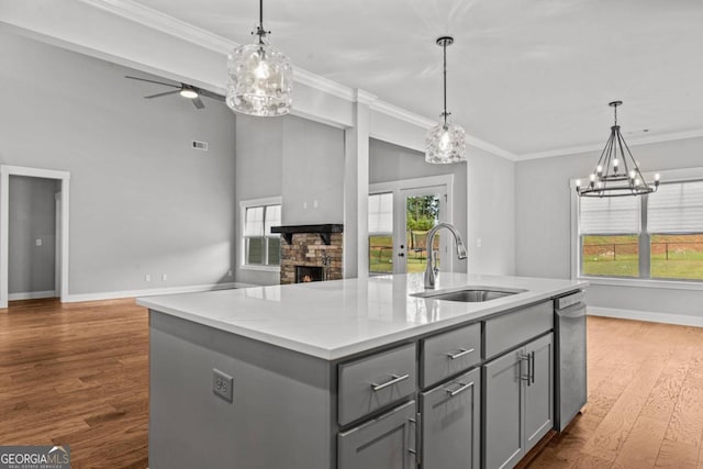 kitchen featuring hardwood / wood-style floors, decorative light fixtures, sink, gray cabinetry, and a center island with sink