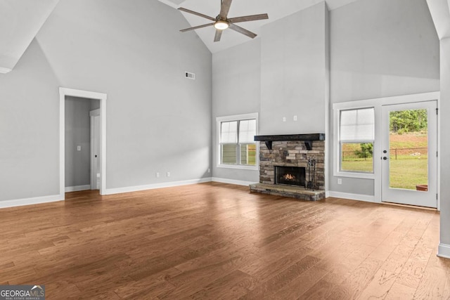 unfurnished living room featuring hardwood / wood-style flooring, ceiling fan, high vaulted ceiling, and a fireplace