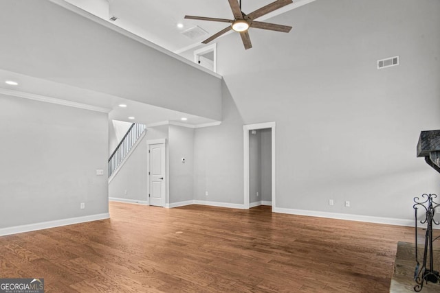 unfurnished living room with hardwood / wood-style floors, ceiling fan, and a high ceiling