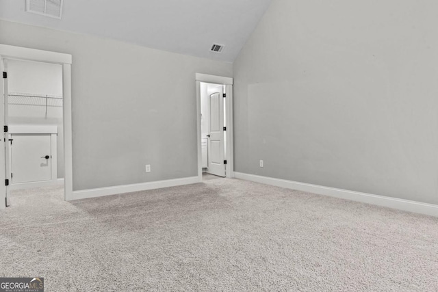 carpeted empty room with high vaulted ceiling