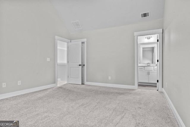 unfurnished bedroom with lofted ceiling, sink, ensuite bath, and light colored carpet